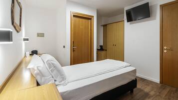 Camera d'albergo con un letto, una scrivania, un armadio e una TV a parete.