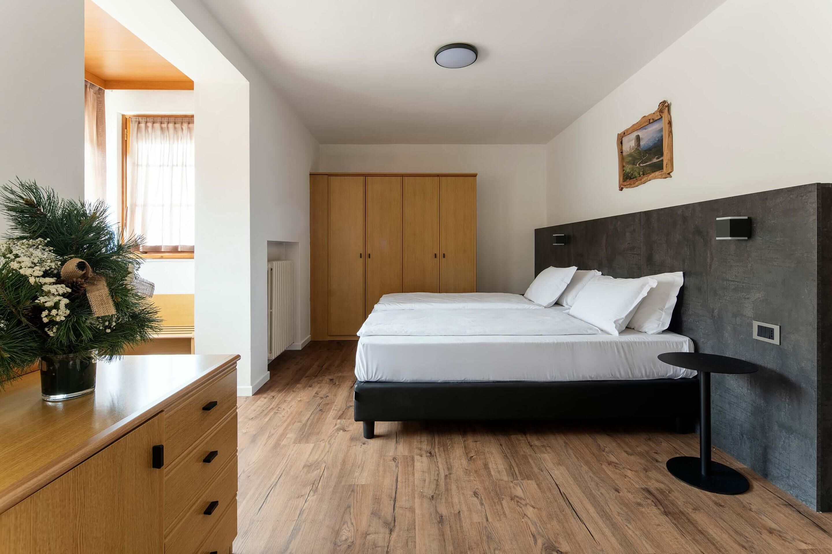 Camera da letto con un letto, un'armadio in legno e un piccolo tavolino.