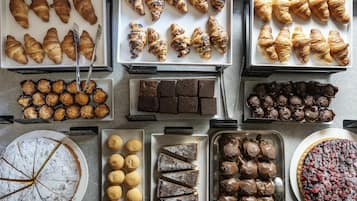 Diversa selección de productos horneados, como cruasanes, muffins, brownies y tartas.
