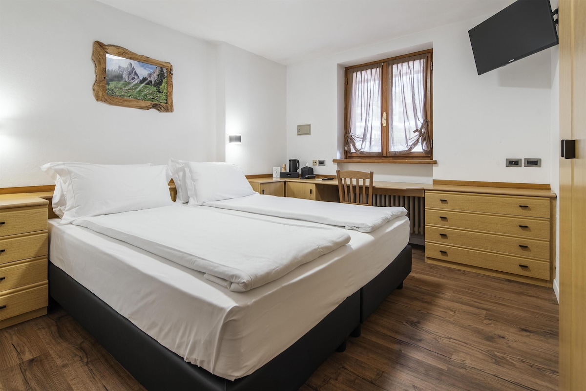 Un dormitorio con cama, escritorio, silla y ventana.
