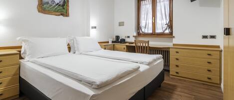 A bedroom with a bed, a desk, a chair, and a window.