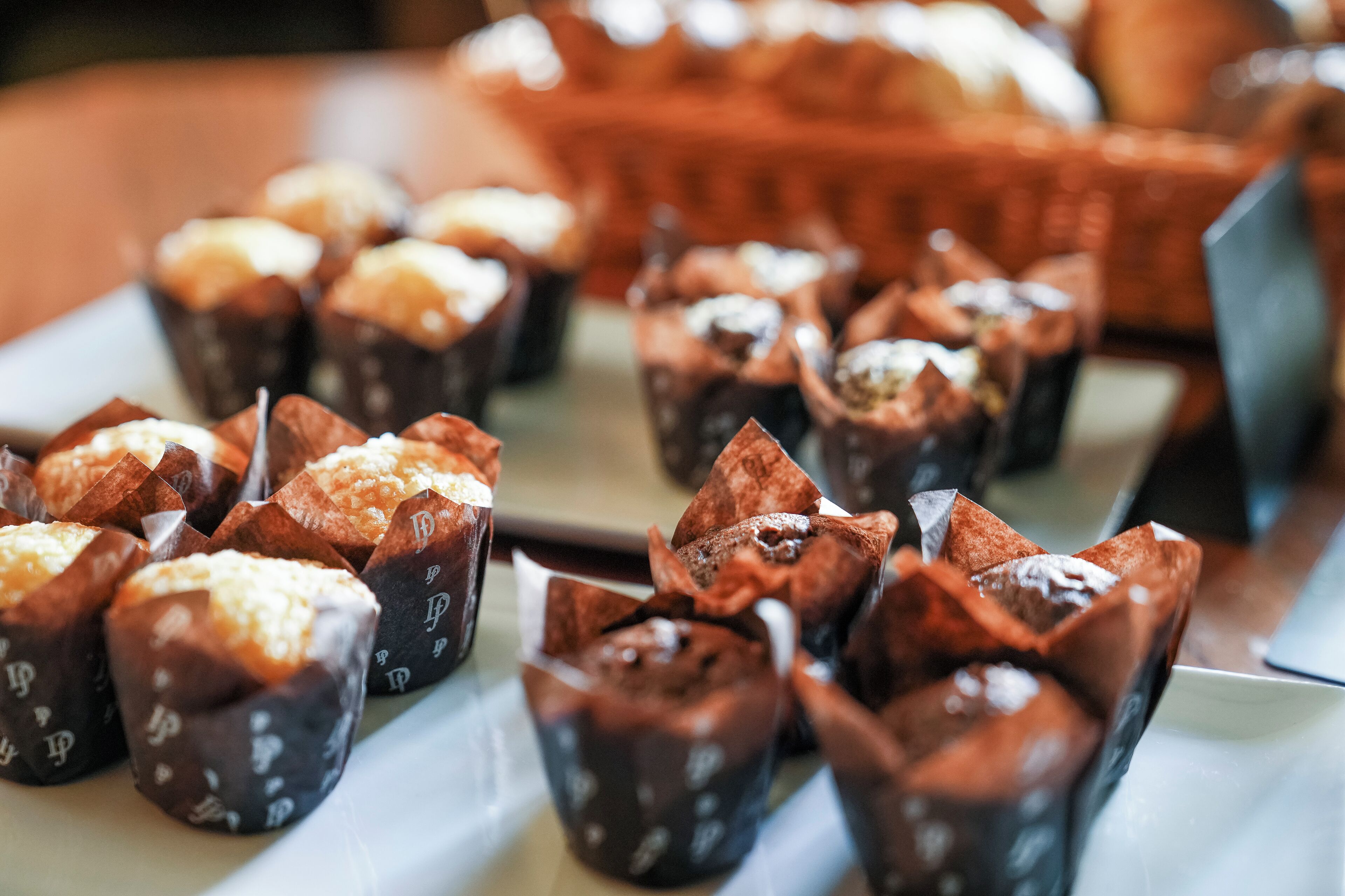 A tray of assorted baked goods, including muffins and pastries, arranged on a white surface.