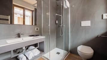 A modern bathroom with a glass-enclosed shower, a white sink, and a toilet.