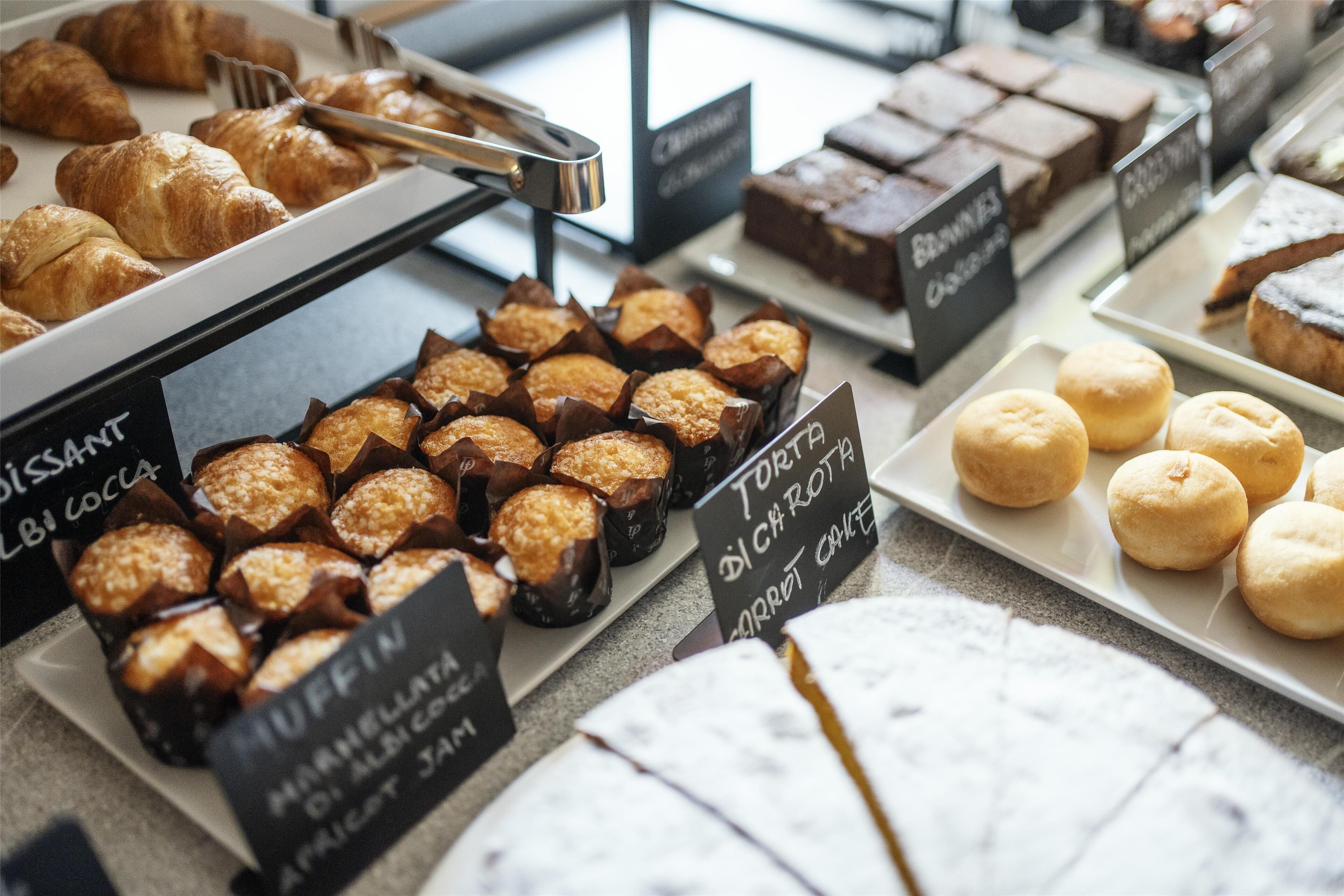 A bakery display with various baked goods like muffins, croissants, and brownies.