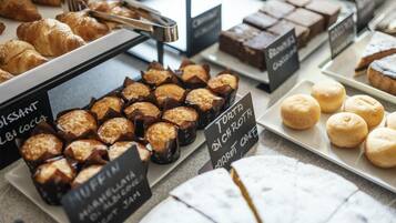 Una vitrina de panadería con una variedad de productos horneados como muffins, croissants y brownies.