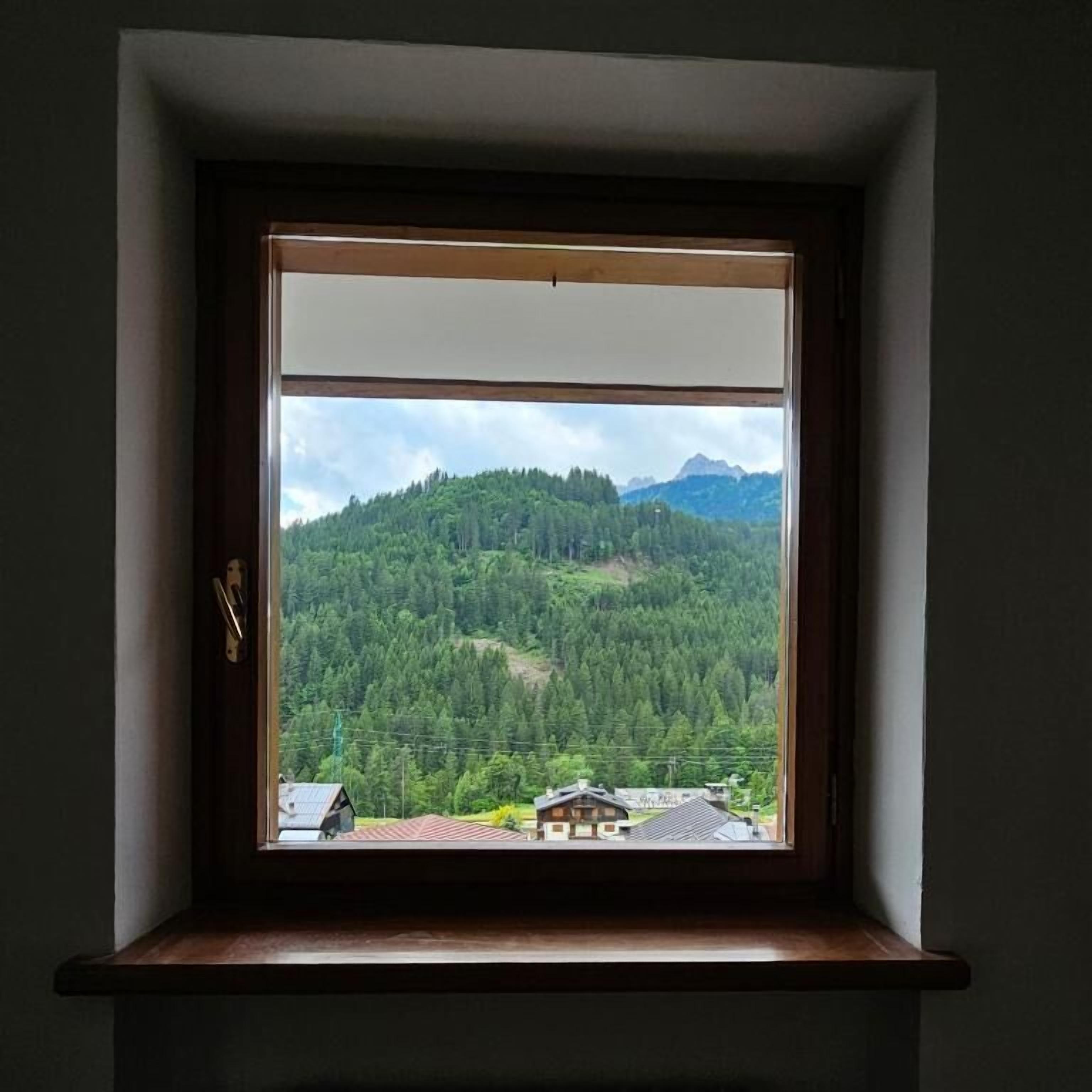 Una finestra amb vista a un paisatge de muntanyes boscanes.