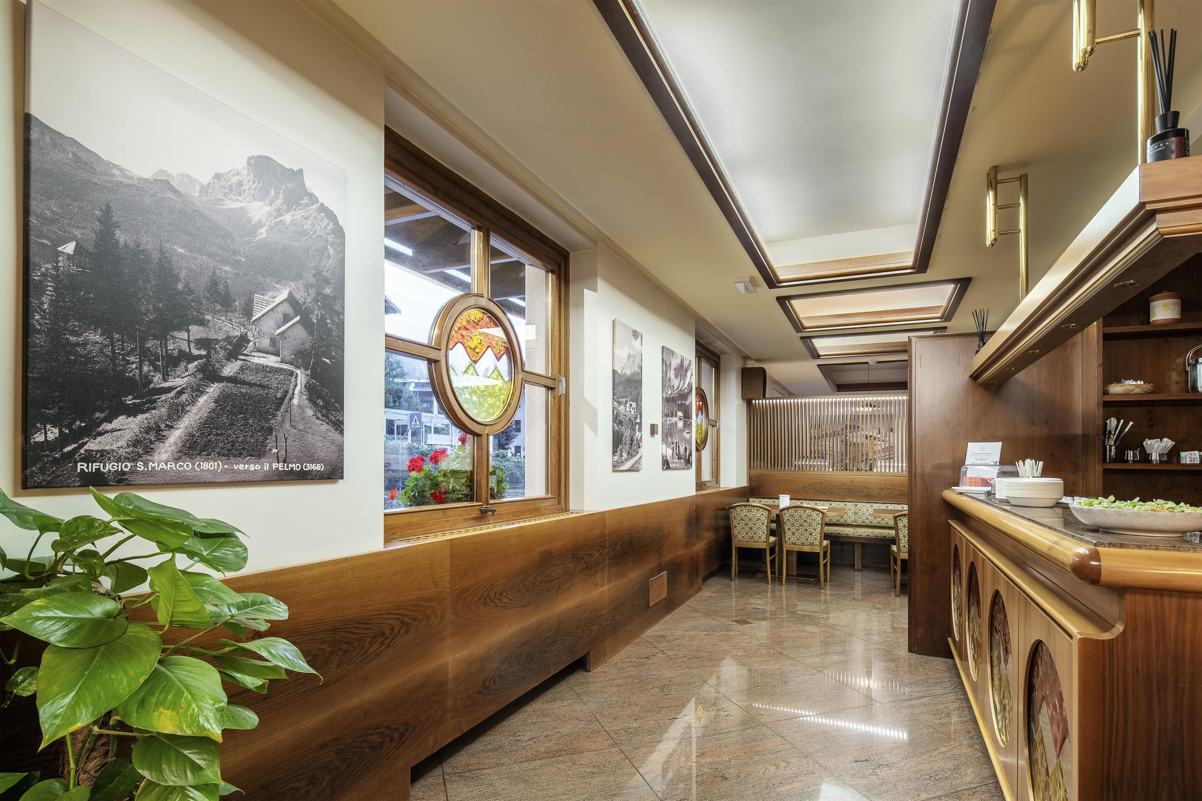 A hotel corridor with wooden paneling, a dining area with patterned chairs, and artwork on the walls.