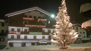 Un hotel con un árbol cubierto de nieve en primer plano, luces iluminadas y un letrero que dice "HOTEL NEVADA".