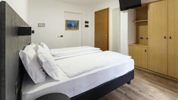 Un dormitorio con una cama, un armario, un televisor y un cuadro en la pared.