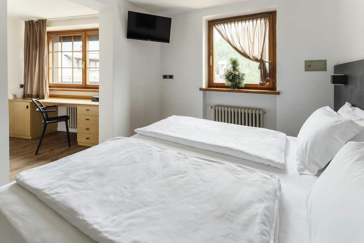 Ein Schlafzimmer mit zwei Betten, einem Schreibtisch, einem Stuhl, einem Heizkörper und einem Fernseher.