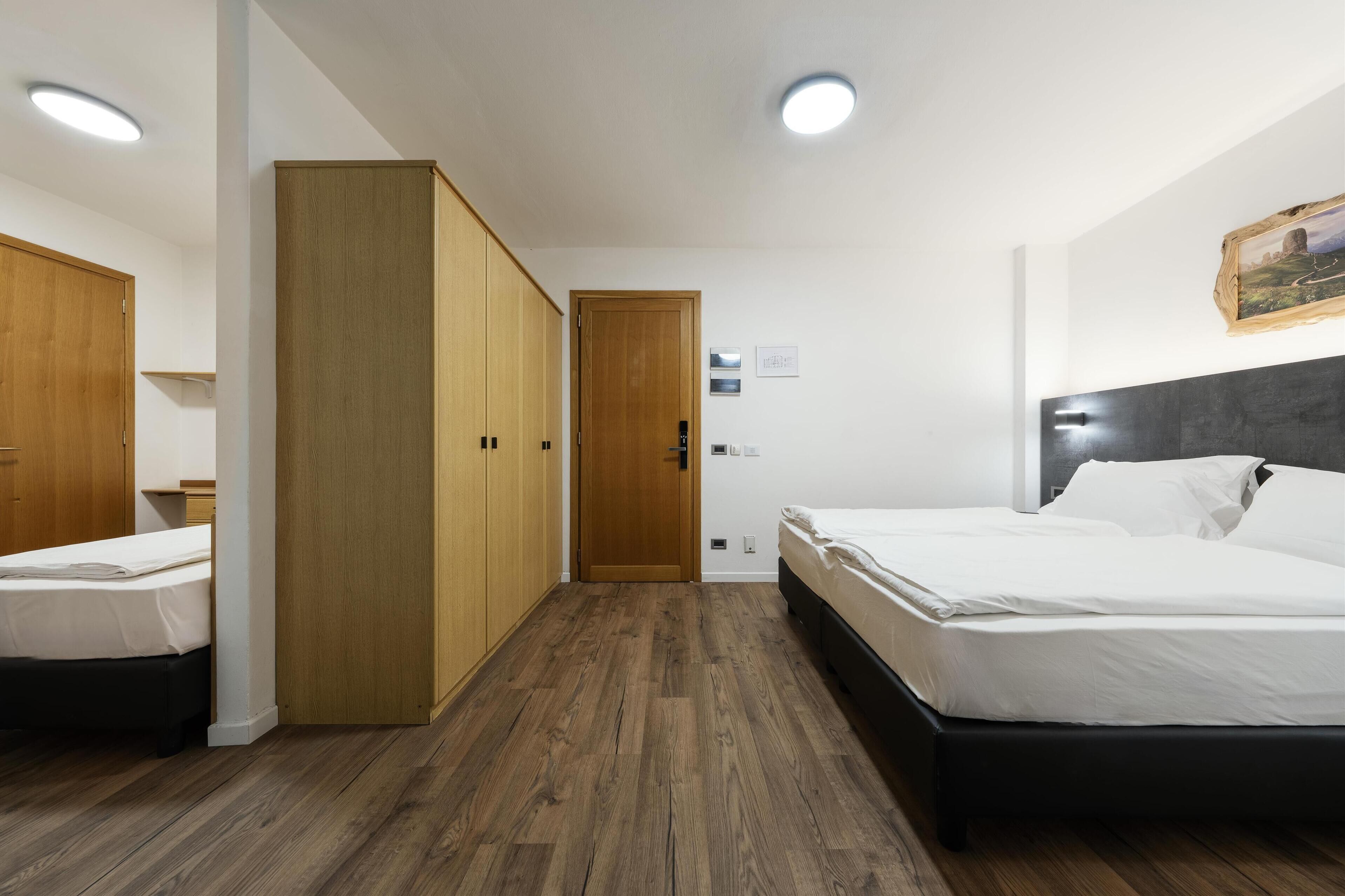 Ein Hotelzimmer mit Holzschrank, einem Bett mit weißer Bettwäsche und Holzboden.