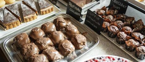 Variedad de postres, incluyendo dulces bañados en chocolate y pastelería, con etiquetas que indican tipos como