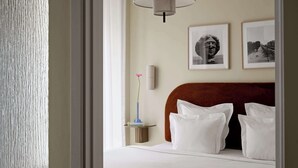 A hotel room with a bed, white pillows, a nightstand with a vase and books, and two framed pictures on the wall. - Two-Bedroom Apartment for 6 (København)