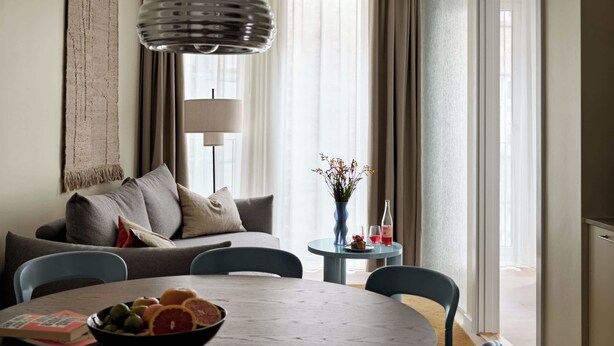 Un salon moderne avec une table à manger ronde, un canapé et une grande fenêtre agrémentée de rideaux.