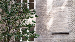 An outdoor seating area with a brick wall, a tree, and a potted plant. - Two-Bedroom Attic Apartment for 4 (København)