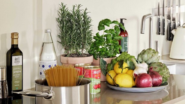 A kitchen counter with various food items, a pot, and a bottle of olive oil. - Attic Two-Bedroom Apartment for 6 (København)