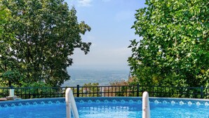 A swimming pool with a view of the ocean, surrounded by lush greenery.