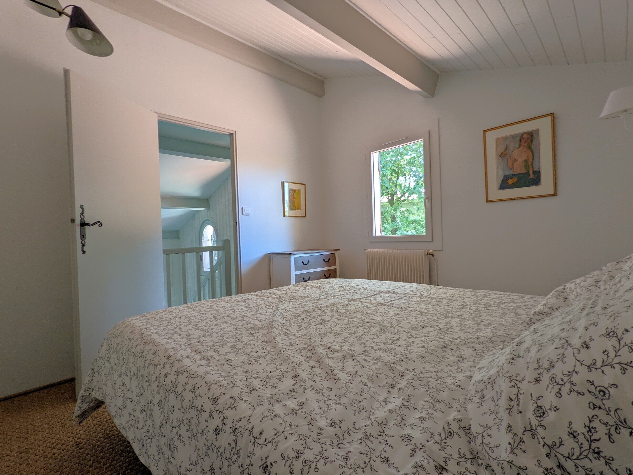 A bedroom with a bed, a dresser, a window, and a door.