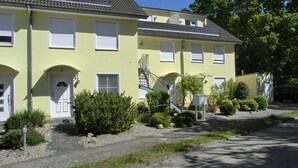 A yellow building with white shutters, a satellite dish, and a small staircase leading to an upper floor. - Apartment for 2 pers. close to the beach approx. 700 m, incl. WLAN (Graal-Müritz)