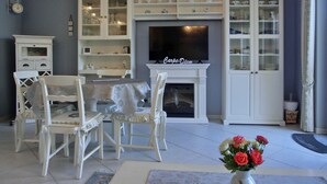 A living room with a TV, white furniture, and a fireplace. - Apartment for 2 pers. close to the beach approx. 700 m, incl. WLAN (Graal-Müritz)