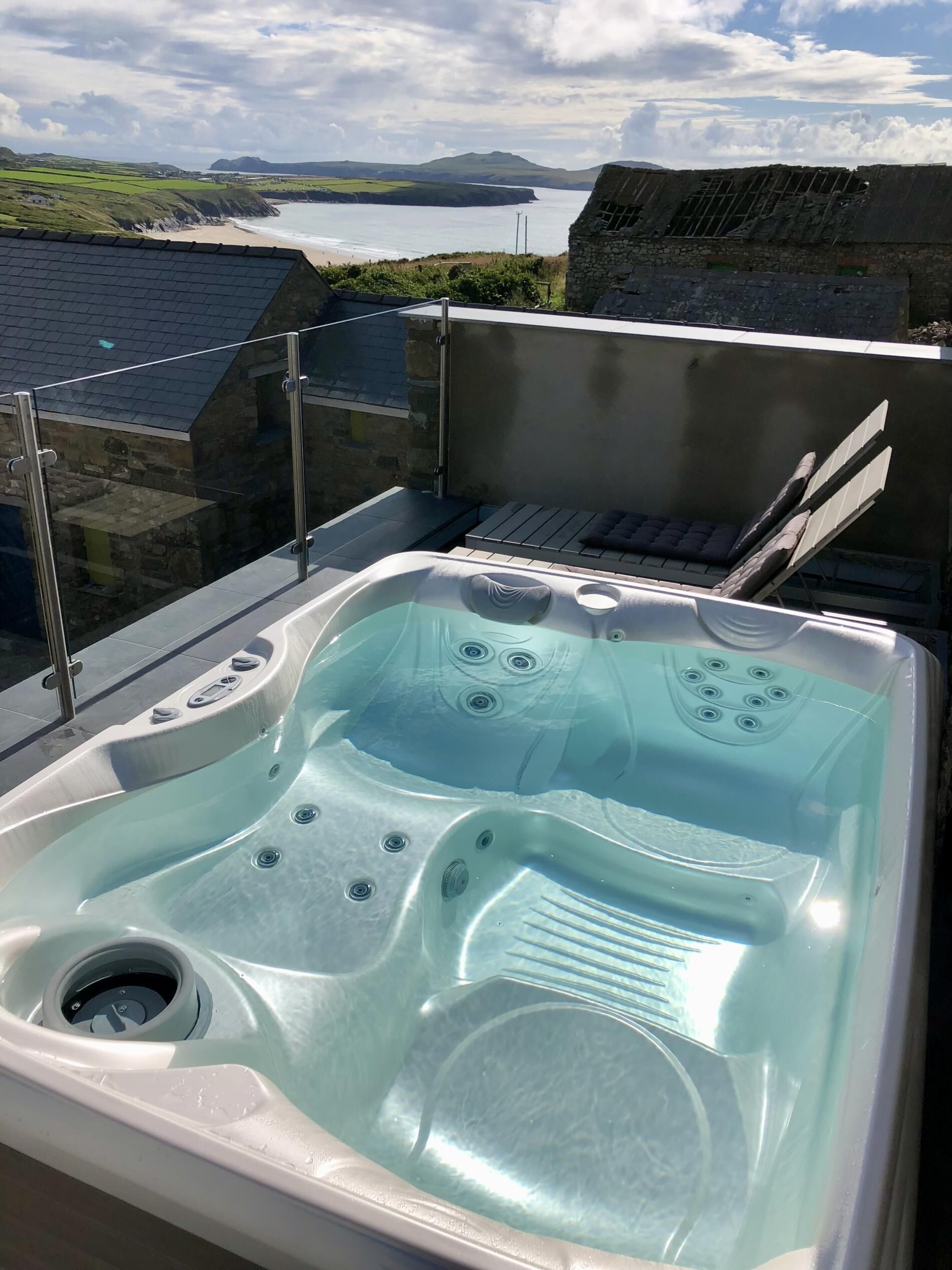 Ein Whirlpool auf einem Balkon mit herrlichem Blick auf das Meer und die Hügel.