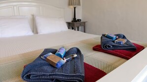 A neatly made bed with a white headboard, a red and blue towel, and toiletries on the bed.