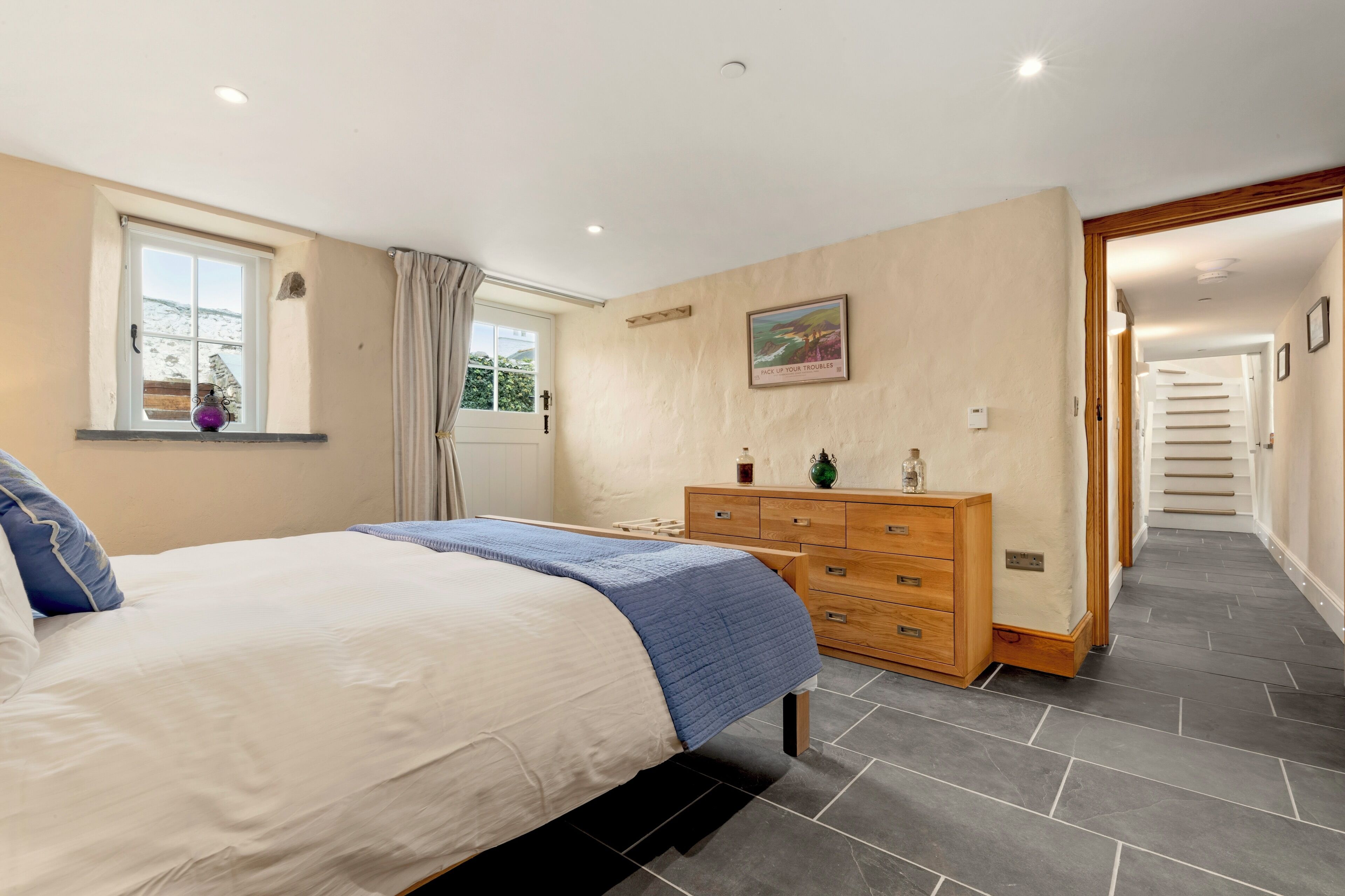 A bedroom with a bed, dresser, and a window with curtains.
