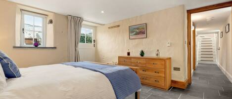 A bedroom with a bed, dresser, and a window with curtains.