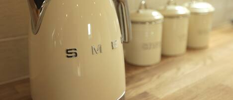 A cream-colored electric kettle with a handle on a wooden countertop.