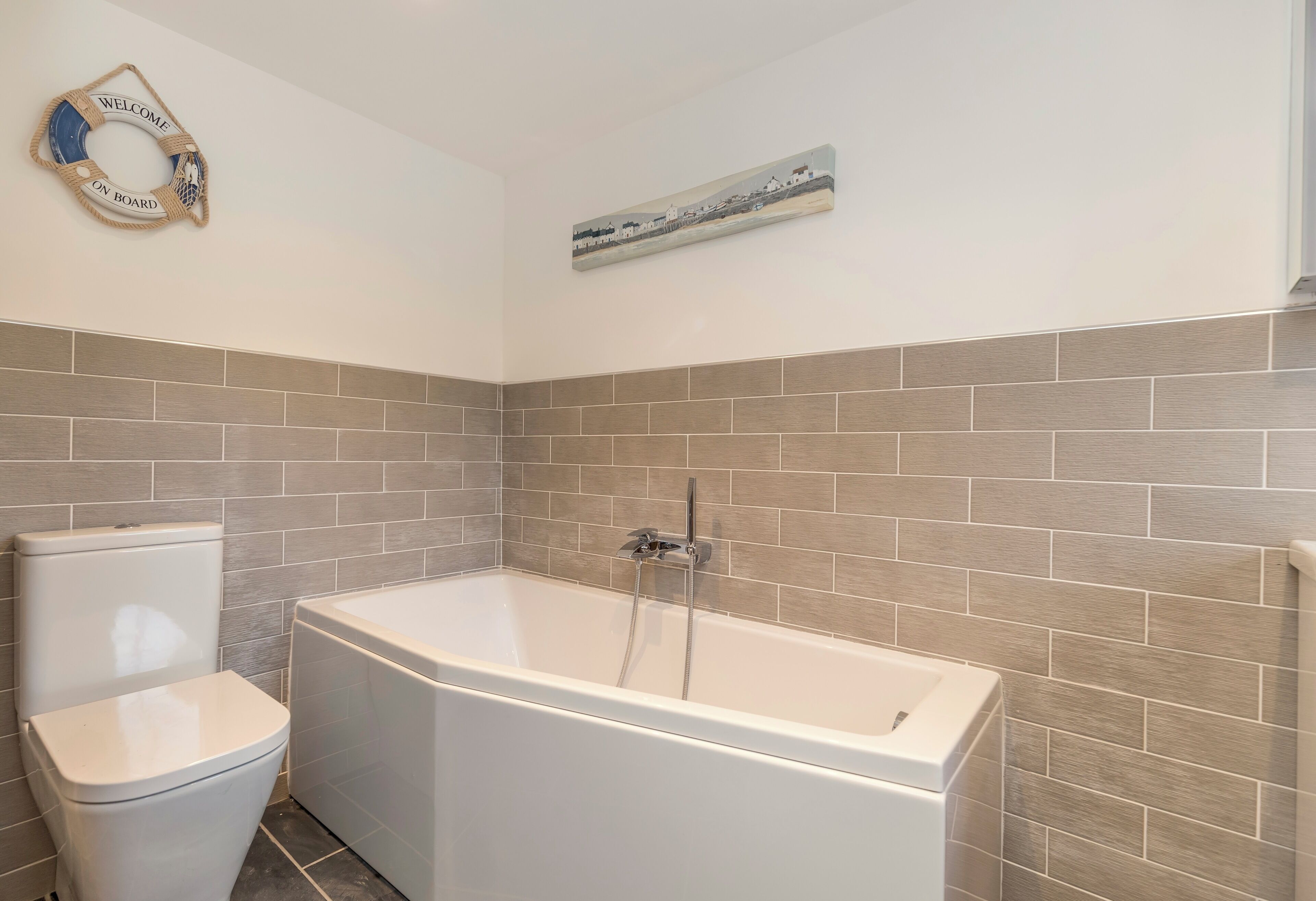 A bathroom with a bathtub, toilet, and a welcome sign.