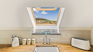 A kitchen with a skylight, a kettle, a toaster, and a sink.