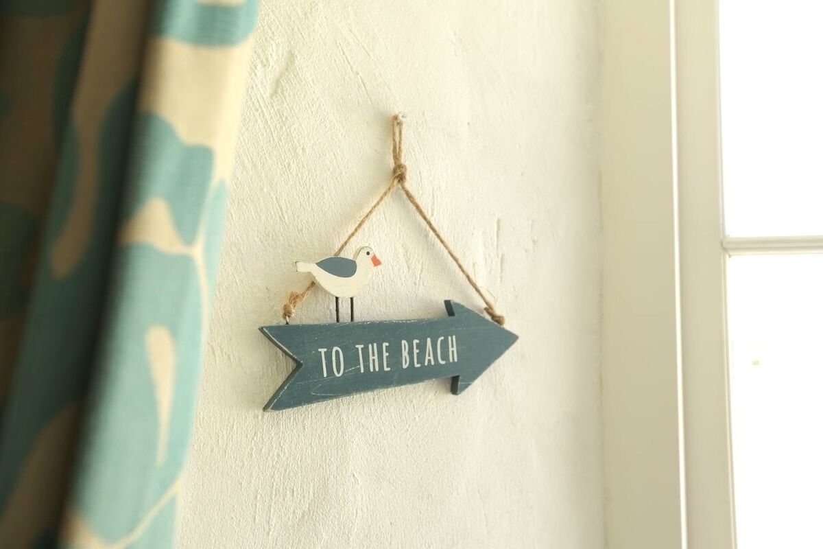 A wall-mounted sign with a bird and the text "TO THE BEACH".