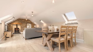 A spacious loft with a high ceiling, exposed stone walls, a fireplace, and a dining area with wooden furniture.