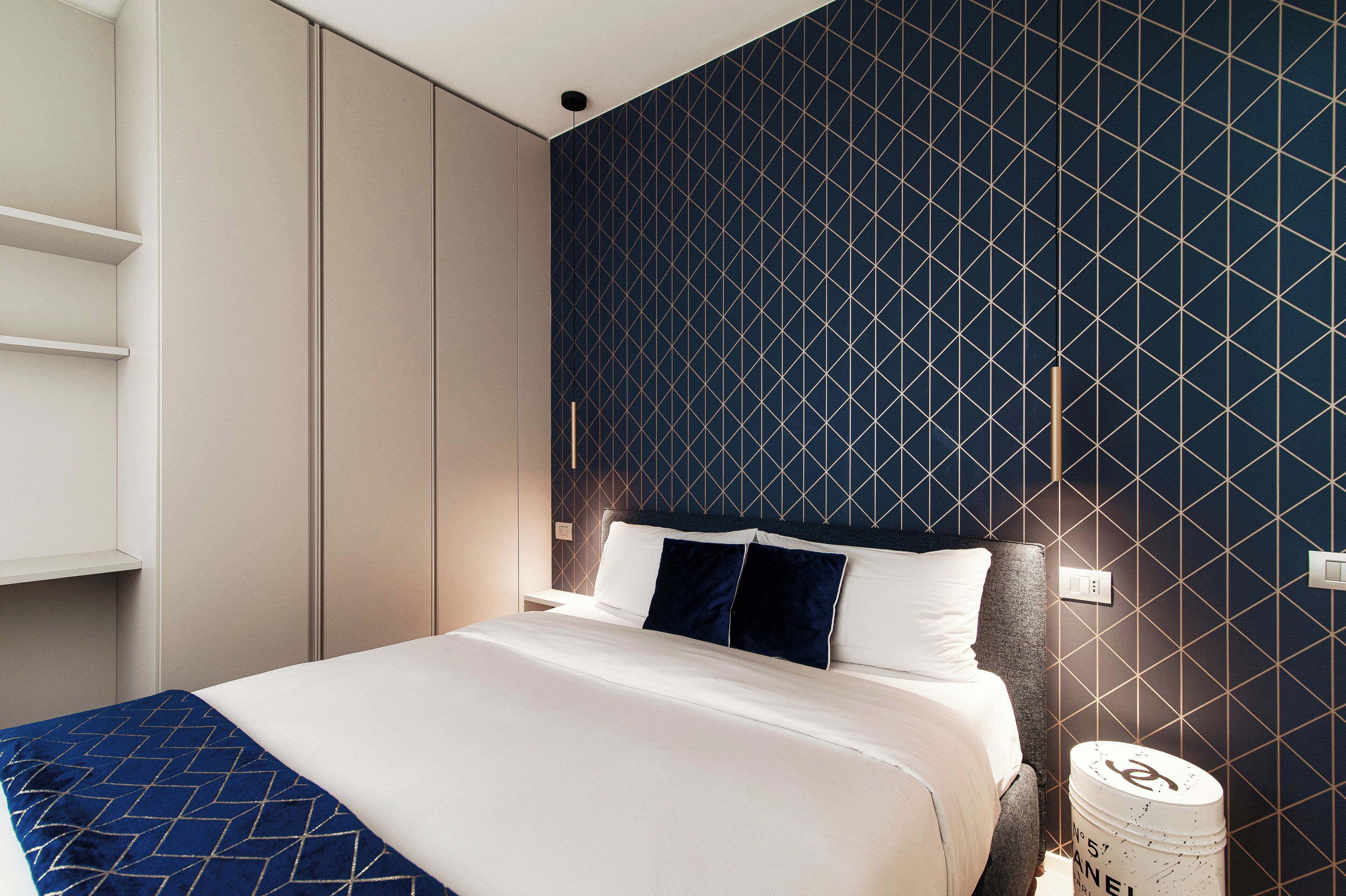 Una habitación de hotel moderna con una pared de diseño geométrico, una cama bien hecha y un estilo minimalista.