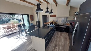A modern kitchen with a large island, black appliances, and pendant lighting.