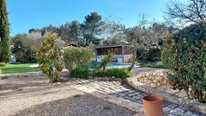 A villa with a swimming pool, surrounded by a well-maintained garden and a stone wall.