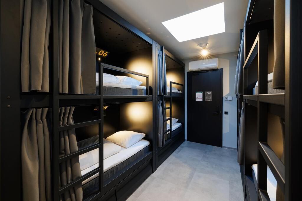A narrow hallway with bunk beds, a skylight, and a door with a sign.