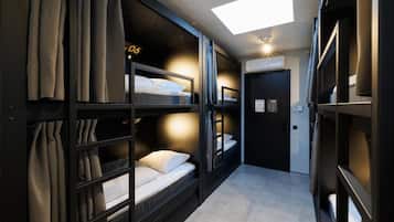 A narrow hallway with bunk beds, a skylight, and a door with a sign.