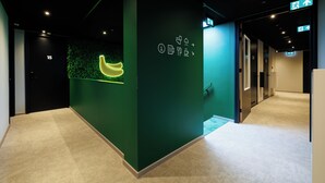 A hallway with a green wall, a neon banana sign, and a door labeled "15".