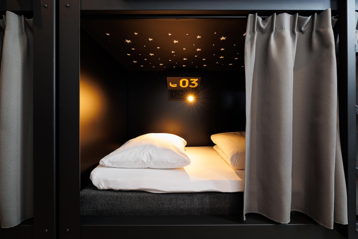 A compact room with a bed, a ceiling with star decorations, and a sign indicating room number 03.
