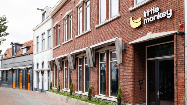A brick building with a storefront labeled "little monkey."