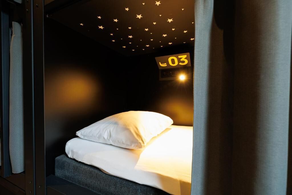 A single bed with white bedding, a star-patterned ceiling, and a sign with the number 03.
