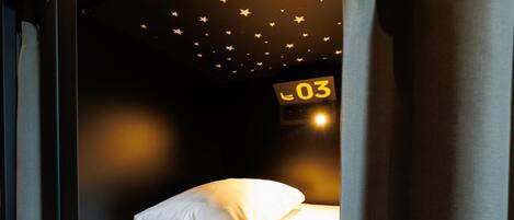 A single bed with white bedding, a star-patterned ceiling, and a sign with the number 03.