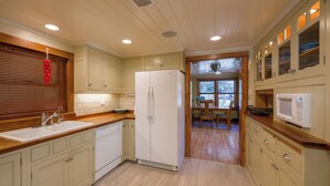 Una cucina con mobili in legno, un frigorifero, un forno a microonde e un'area pranzo con una finestra.