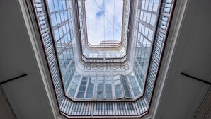 Un atrium à plusieurs niveaux, doté d’une verrière centrale et de rampes en verre.
