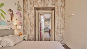 Une chambre d’hôtel avec un grand lit, une table de chevet, une lampe et une fresque murale.