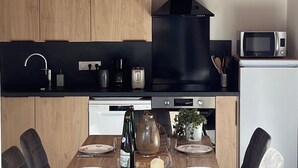 A modern kitchen with wooden cabinets, a black range hood, and a dining area with a table set for four.