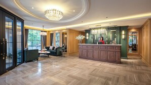 A spacious lobby with a grand chandelier, a reception desk, and a seating area with a sofa and coffee table. - Saigon Aroma Hotel (Hanoi)