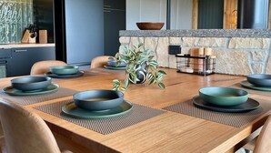 A modern dining area with a wooden table, matching chairs, and a central plant.