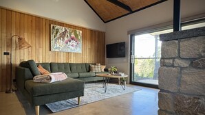 A modern living room with a green sectional sofa, a small round table, and a stone wall.